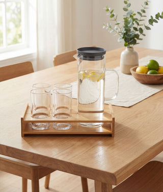 Minimalistische Glaskaraffe und passende Trinkgläser auf einem Holztablett für ein ästhetisches Home & Living Ambiente.