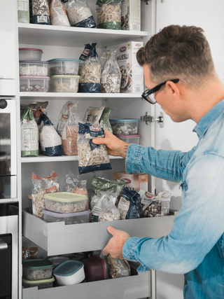 Unorganisierter Küchenschrank mit angebrochenen Plastikverpackungen und unordentlichen Vorräten vor der Organisation.