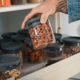 Perfekte Schubladen-Ordnung: Eine tätowierte Hand hebt ein 500ml Vorratsglas aus einem organisierten Auszug mit einheitlichem HATTY HAYS System.